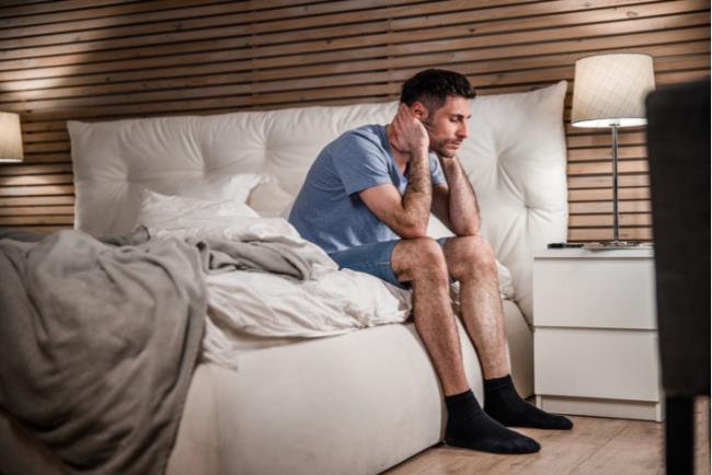 גבר סובל ממצב רוח ירוד ונמצא בסיכון לדיכאון בשל שעות שינה לא סדירות 